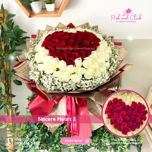 Bouquet with red and white roses shaped like a heart, surrounded by white fillers, on a light background.
