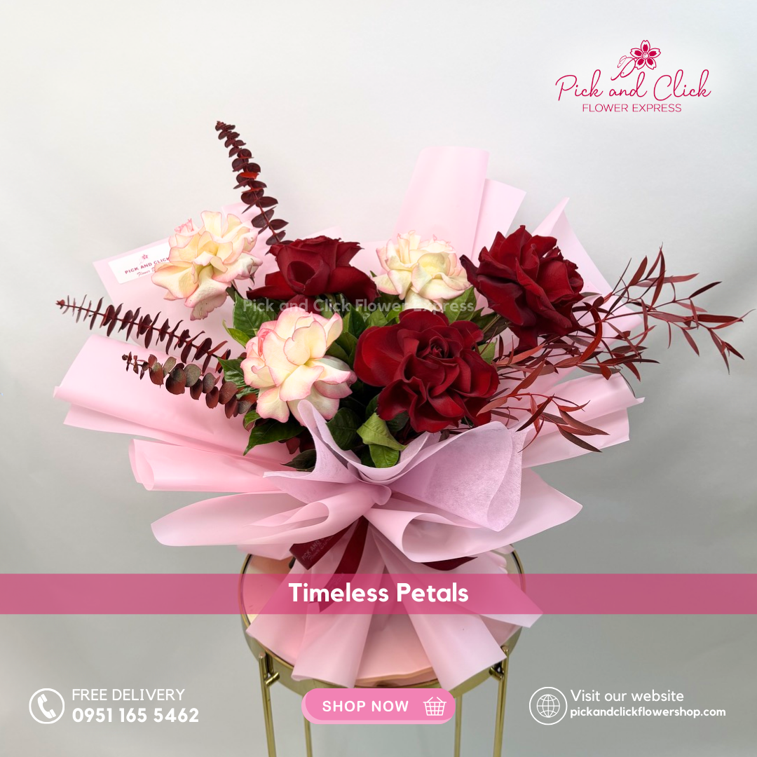 Timeless Petals Bouquet featuring two tone pink roses and imported red roses accented with rosal, red sprayed eucalyptus, and parvi leaves in an elegant hand bouquet.